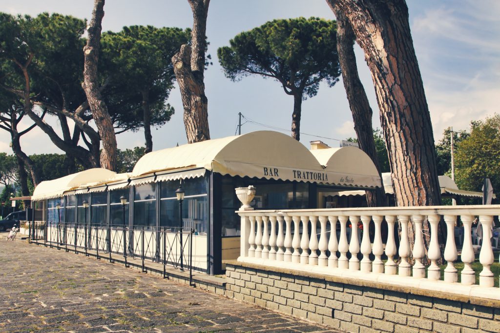 Trattoria con terrazza, alberi e cielo sereno.