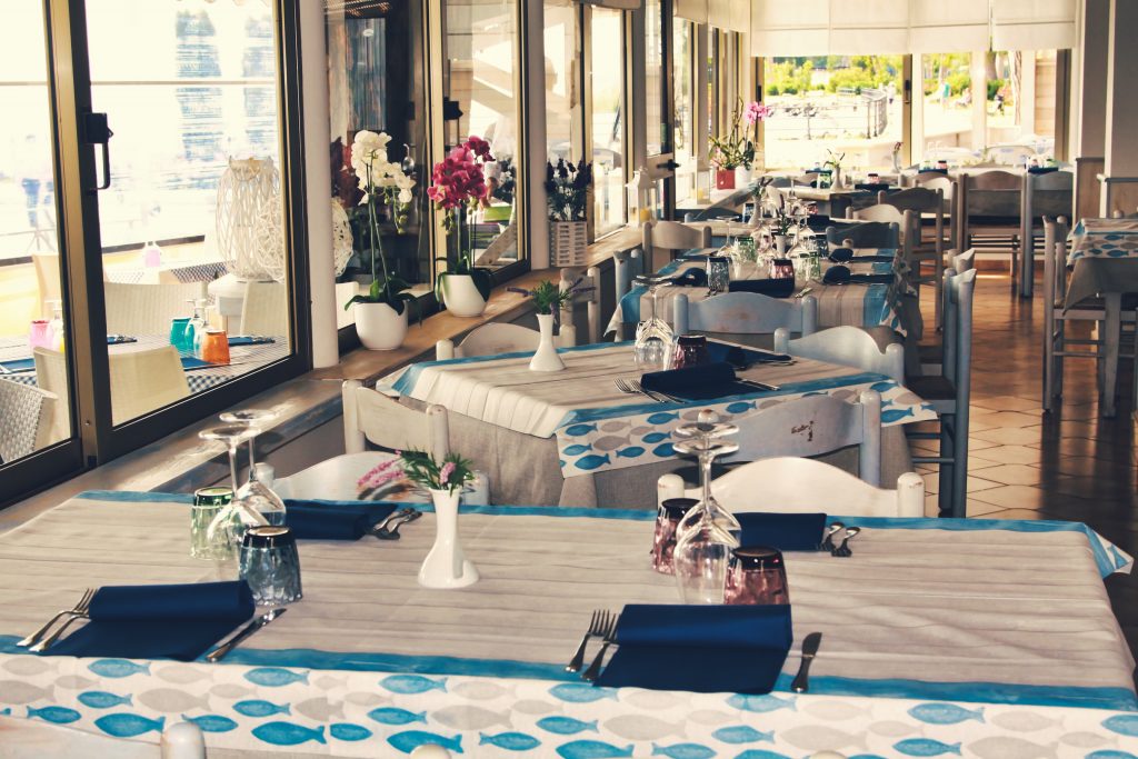 Tavoli apparecchiati in un ristorante con fiori e tovaglie.