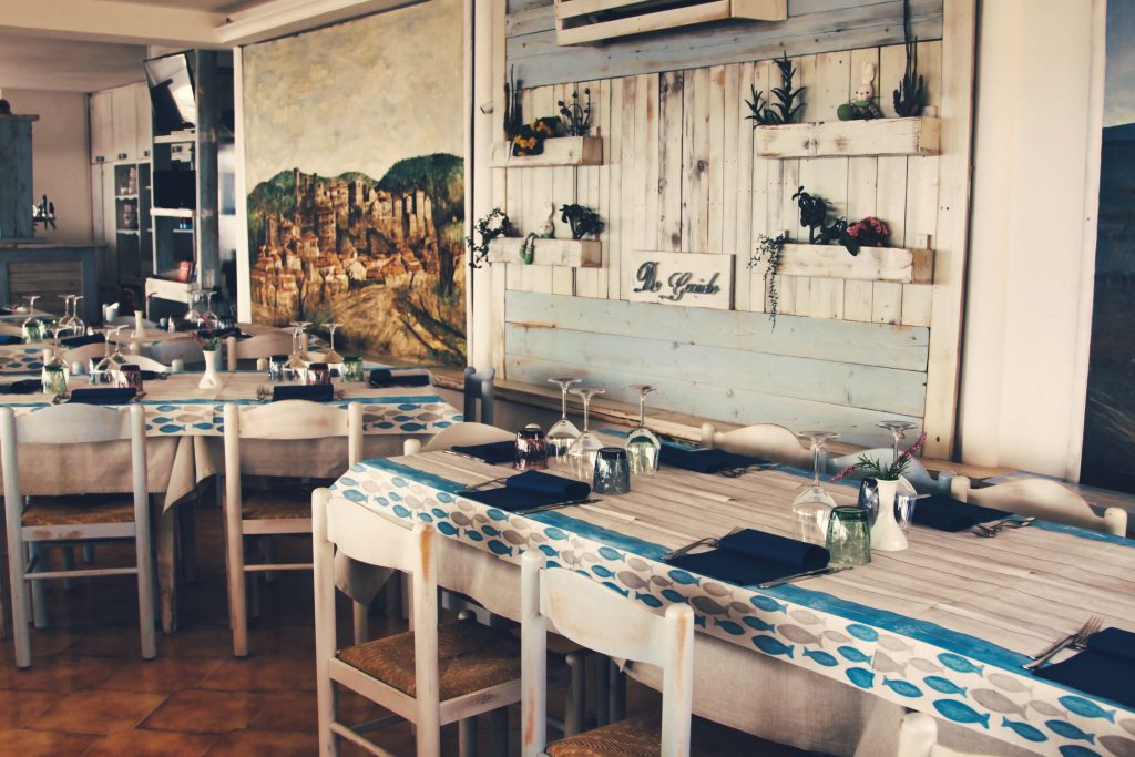 Ristorante con tavoli apparecchiati e decorazioni rustiche.