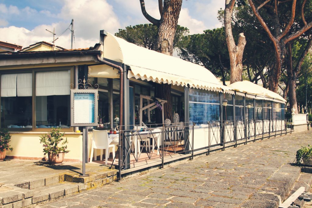 Ristorante all'aperto con veranda e tavoli apparecchiati.
