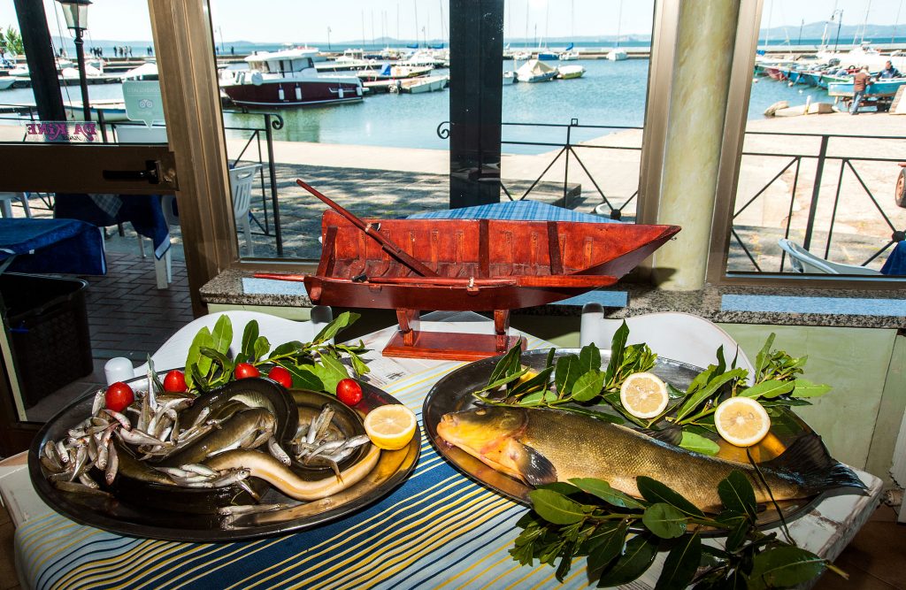 Piatti di pesce fresco con decorazioni, vista porto.