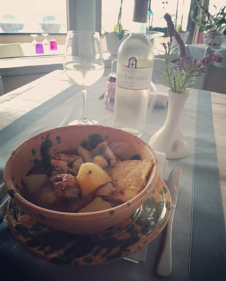 Ciotola di cibo con vino bianco su tavola apparecchiata.