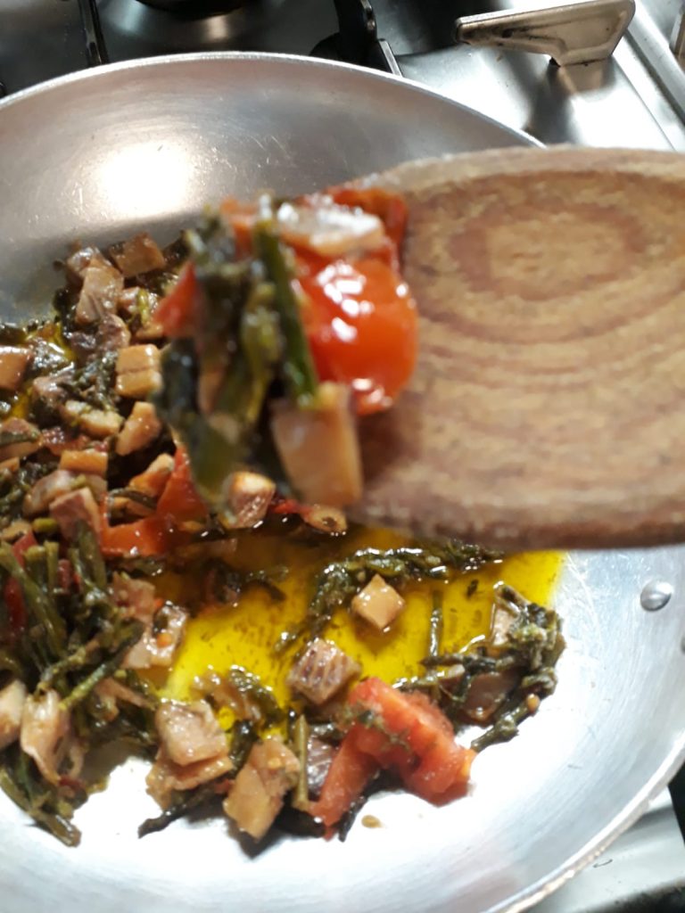 Padella con verdure e pomodori in cottura.