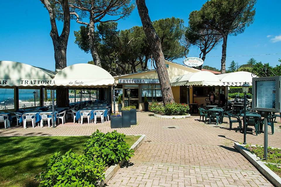 Esterno di una trattoria con tavoli all'aperto.