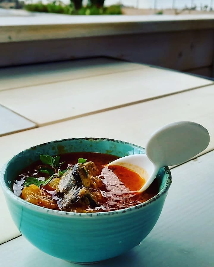 Ciotola di zuppa con cucchiaio su tavolo.