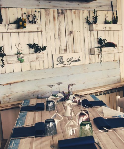 Tavolo apparecchiato in ristorante con decorazioni rustiche.