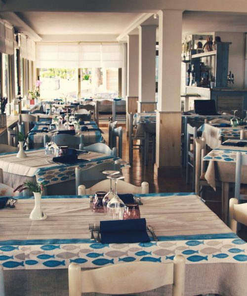 Interno di un ristorante con tavoli apparecchiati.