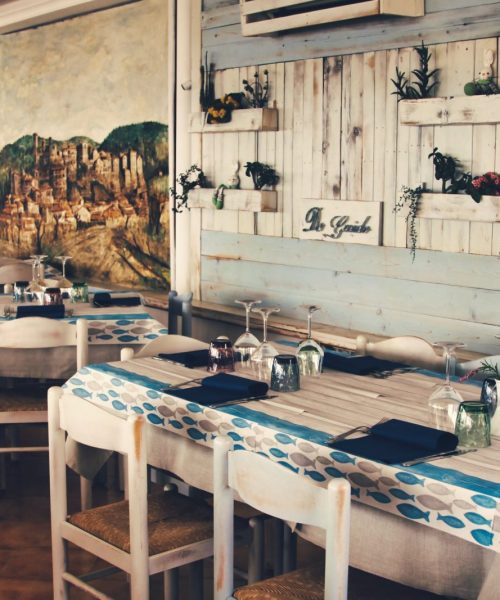 Ristorante con tavoli apparecchiati e decorazioni rustiche.