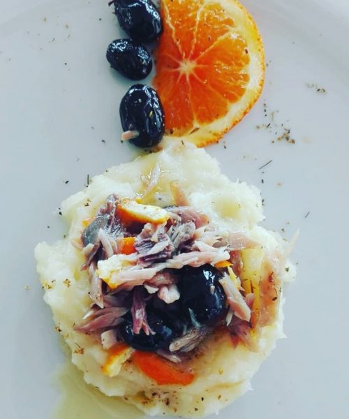 Purè con tonno, olive, fetta d'arancia su piatto.
