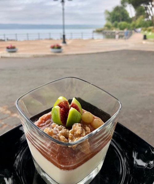 Dessert in bicchiere con frutta e noci, vista mare.