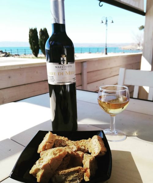 Bottiglia di vino, bicchiere e biscotti su tavolo esterno.