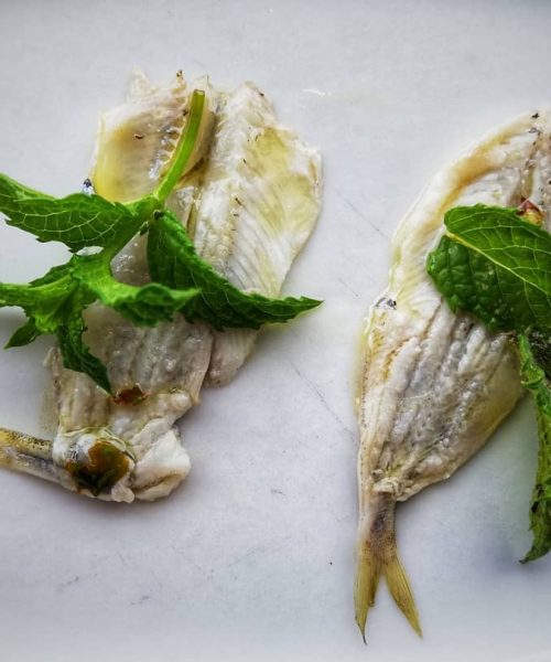 Due filetti di pesce con foglie di menta.