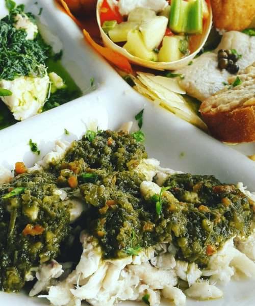 Piatto di pesce con verdure e salse verdi.